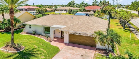 A residential house with a tiled roof, a garage, and a front yard with a palm tree.