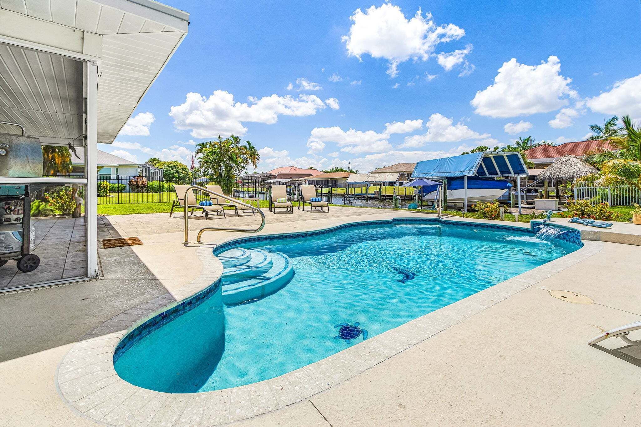 A swimming pool with a slide, lounge chairs, and a covered area.