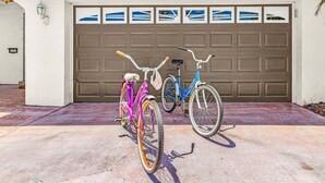 Two bicycles parked in front of a garage with a decorative window. - Gulf Access Escape with Heated Pool, Dock & Kayaks - Villa Maria - Roelens (Cape Coral)
