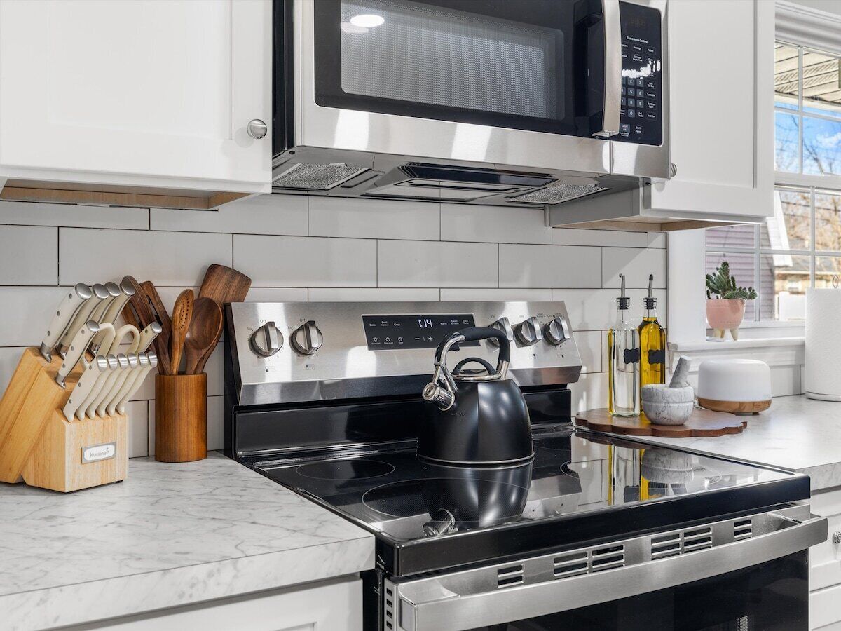 A modern kitchen with a stainless steel stove, a microwave above it, and a kettle on the stove.