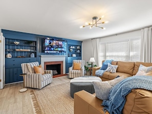A living room with a fireplace, blue walls, and a television mounted on the wall.