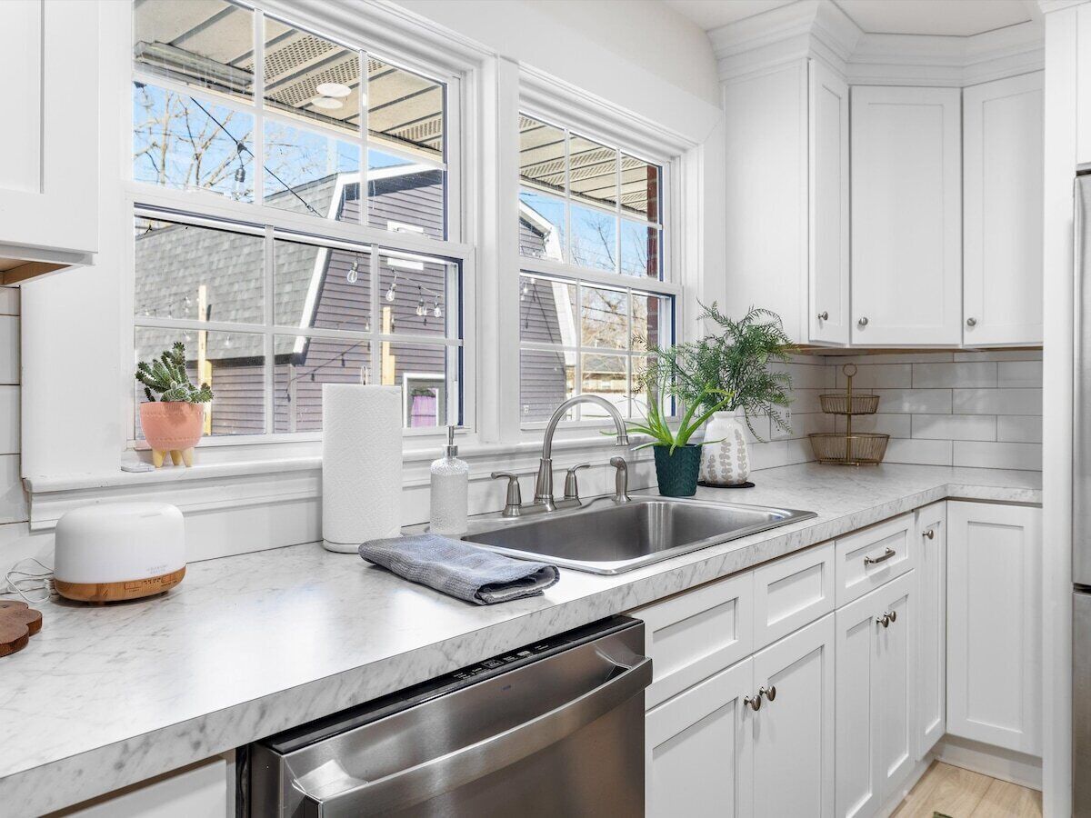 A modern kitchen with white cabinetry, a double sink, and a dishwasher.