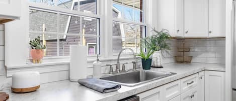 A modern kitchen with white cabinetry, a double sink, and a dishwasher.