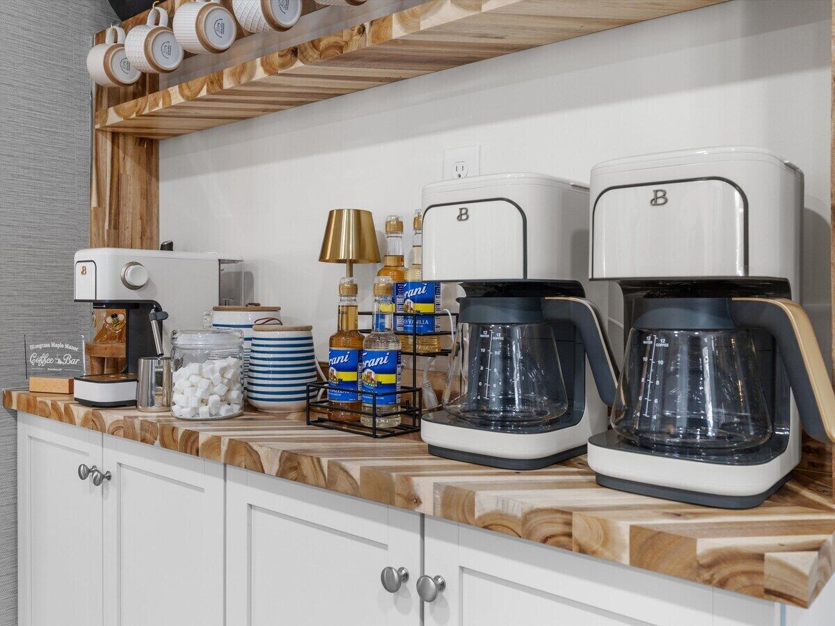 A kitchen counter with two coffee makers, a coffee machine, a lamp, and various kitchen items.
