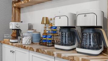 A kitchen counter with two coffee makers, a coffee machine, a lamp, and various kitchen items.