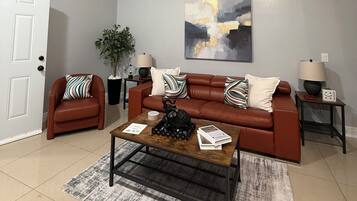 Un salon avec un canapé en cuir marron, une table basse et un tableau accroché au mur.