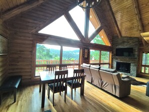Un interior de madera con comedor, sofá y chimenea.