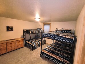 Habitación con literas, cómoda y una lámpara en el techo.