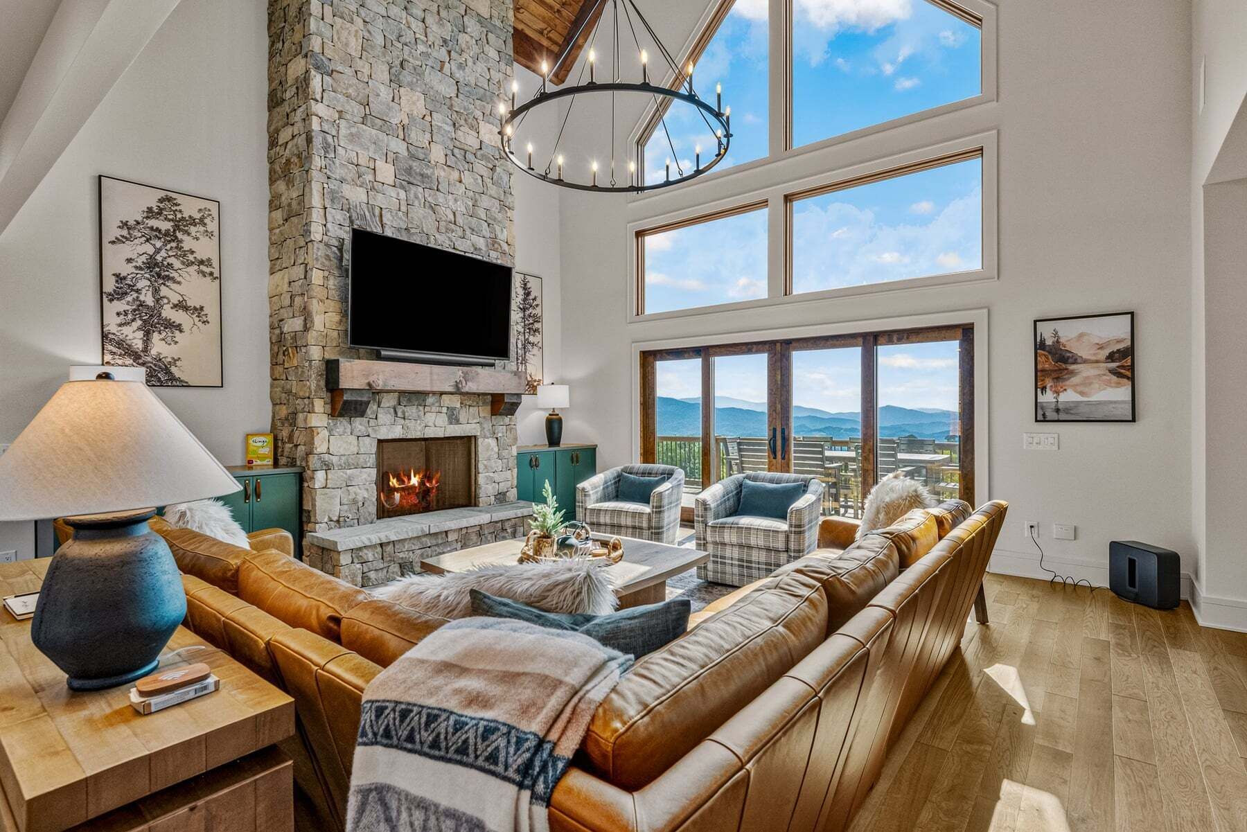 Un salón amplio con chimenea de piedra, asientos cómodos y ventanas grandes con vistas a las montañas.