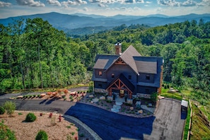 A large, two-story house with a stone foundation, surrounded by a well-maintained garden and a driveway. - Ridge & Repeat Lodge at Eagles Nest - hot tub, in+out fireplace, firepit, views (Banner Elk)