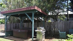Un'area barbecue esterna coperta, con griglia e posti a sedere.
