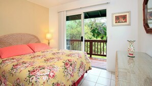 Un dormitorio con cama, mesita de noche, lámpara, ventana y balcón.