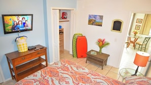 Una camera d'albergo con un letto, una televisione, una scrivania, un armadio, un tavolino con un vaso e una sedia.