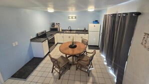 Una cucina compatta con zona pranzo, che include un'isola centrale, un frigorifero e un forno a microonde.