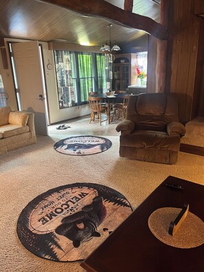 Una sala de estar acogedora con chimenea, un comedor con mesa y sillas, y un ventanal con cortinas.