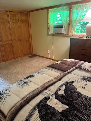 Un dormitorio con cama, armario de madera y ventana con cortinas.