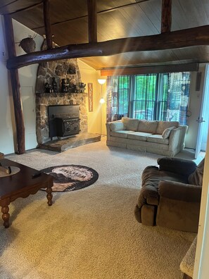 A cozy living room with a stone fireplace, a sofa, and a coffee table. - Adorable 2-bedroom lake house with Lake Access near Confluence (Confluence)