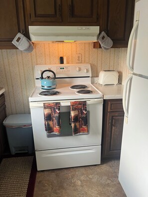 A kitchen with a white stove, a toaster, and a refrigerator. - Adorable 2-bedroom lake house with Lake Access near Confluence (Confluence)