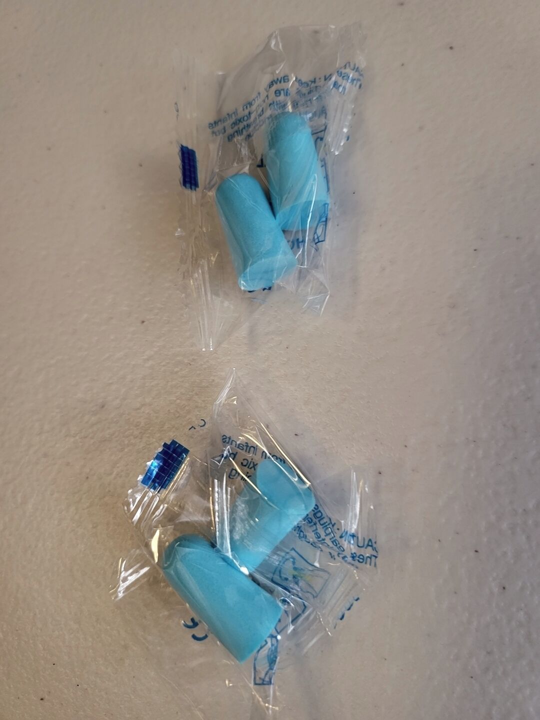Kolme muovikalvolla päällystettyä esinettä beigenvärisellä alustalla.