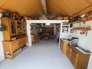 A rustic kitchen with wooden cabinets, a dining area with stools, and various kitchen utensils displayed on shelves.