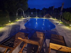 An outdoor swimming pool with a wooden deck and lounge chairs.