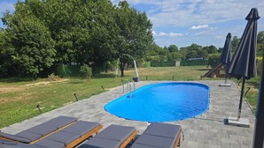 En swimmingpool med solstolar och ett avskärmat område.