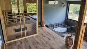 En modern inredning med trägolv, en glasveranda med ett bubbelbad, en hängmatta och en hängande lampa.