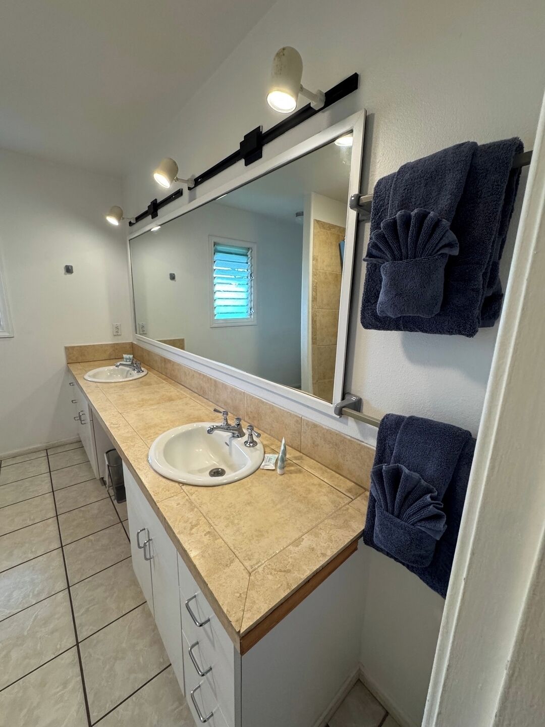 A bathroom with two sinks, a large mirror, and towels hanging on the wall.