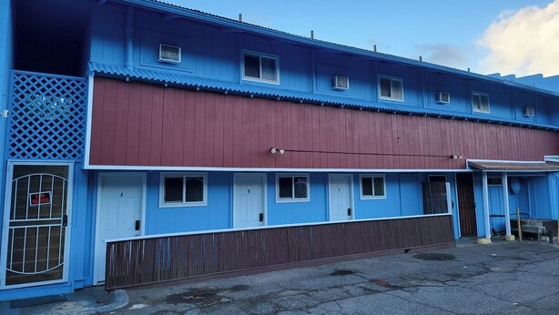 Een meerhoog gebouw met een blauwe gevel en een rood bovenstuk, met een hek voor de ingang.