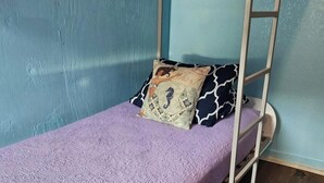 Een stapelbed met een paars dekbedovertrek en gestreepte kussens.