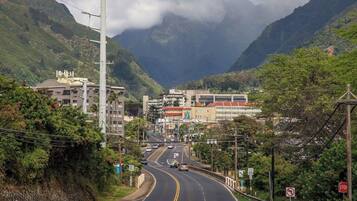 Una carretera con vehículos, edificios y montañas al fondo.