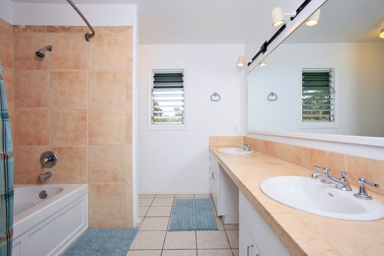 A bathroom with a bathtub, two sinks, a shower, and a large mirror.