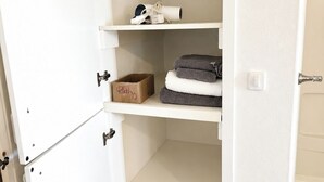 Een witte kast met planken, een schoenenrek en een doos met de tekst 'Bad'. 