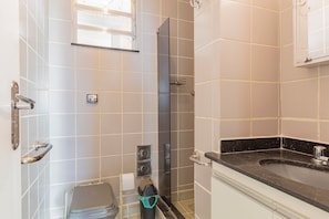 Ein Badezimmer mit Dusche, Toilette, Waschbecken und einem Fenster.