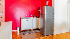Una cocina compacta equipada con refrigerador, cafetera y microondas.