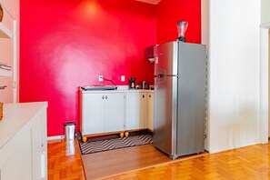 Eine kleine Küche mit Kühlschrank, Kaffeemaschine und Mikrowelle.