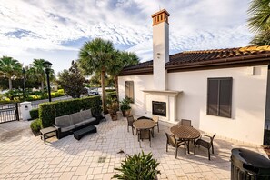 A patio with a sofa, table, chairs, and a fireplace. - Soak Up the Sun! Luxury 8BR Villa & South Pool (Kissimmee)