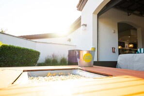 A patio with a fire feature, a metal bucket with a label, and a building entrance. - Soak Up the Sun! Luxury 8BR Villa & South Pool (Kissimmee)