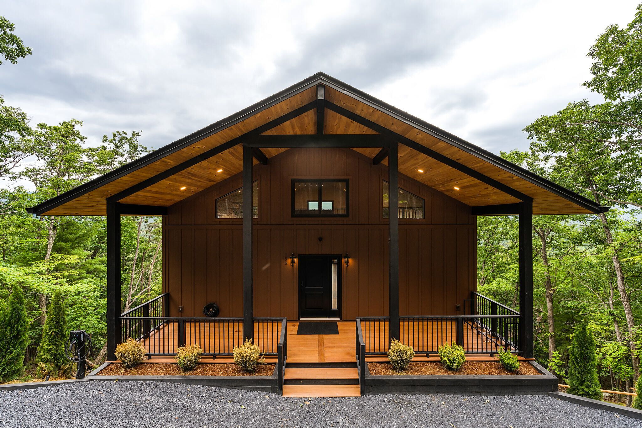 Une cabane en bois avec une véranda, une porte d’entrée et une petite fenêtre.