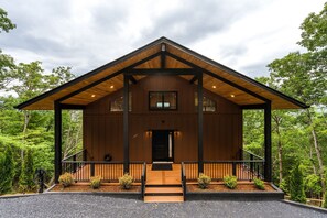 Une cabane en bois avec une véranda, une porte d’entrée et une petite fenêtre.