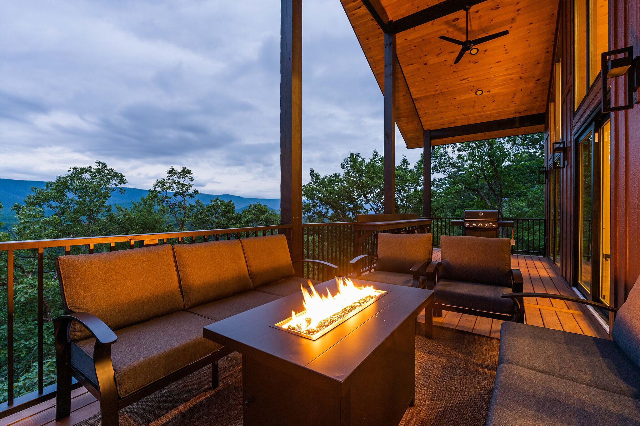 Une terrasse extérieure dotée d’un foyer, de sièges et offrant une vue sur les montagnes.