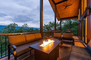 Une terrasse extérieure dotée d’un foyer, de sièges et offrant une vue sur les montagnes.