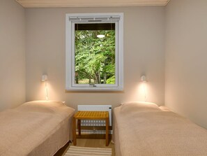 A room with two beds, a radiator, and a window with a view of trees. - "Lonneke" -  from the sea by Interhome (Hals)