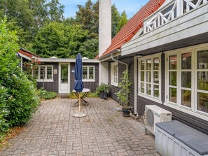 A courtyard with a brick floor, a blue umbrella, and a white air conditioning unit. - "Lonneke" -  from the sea by Interhome (Hals)