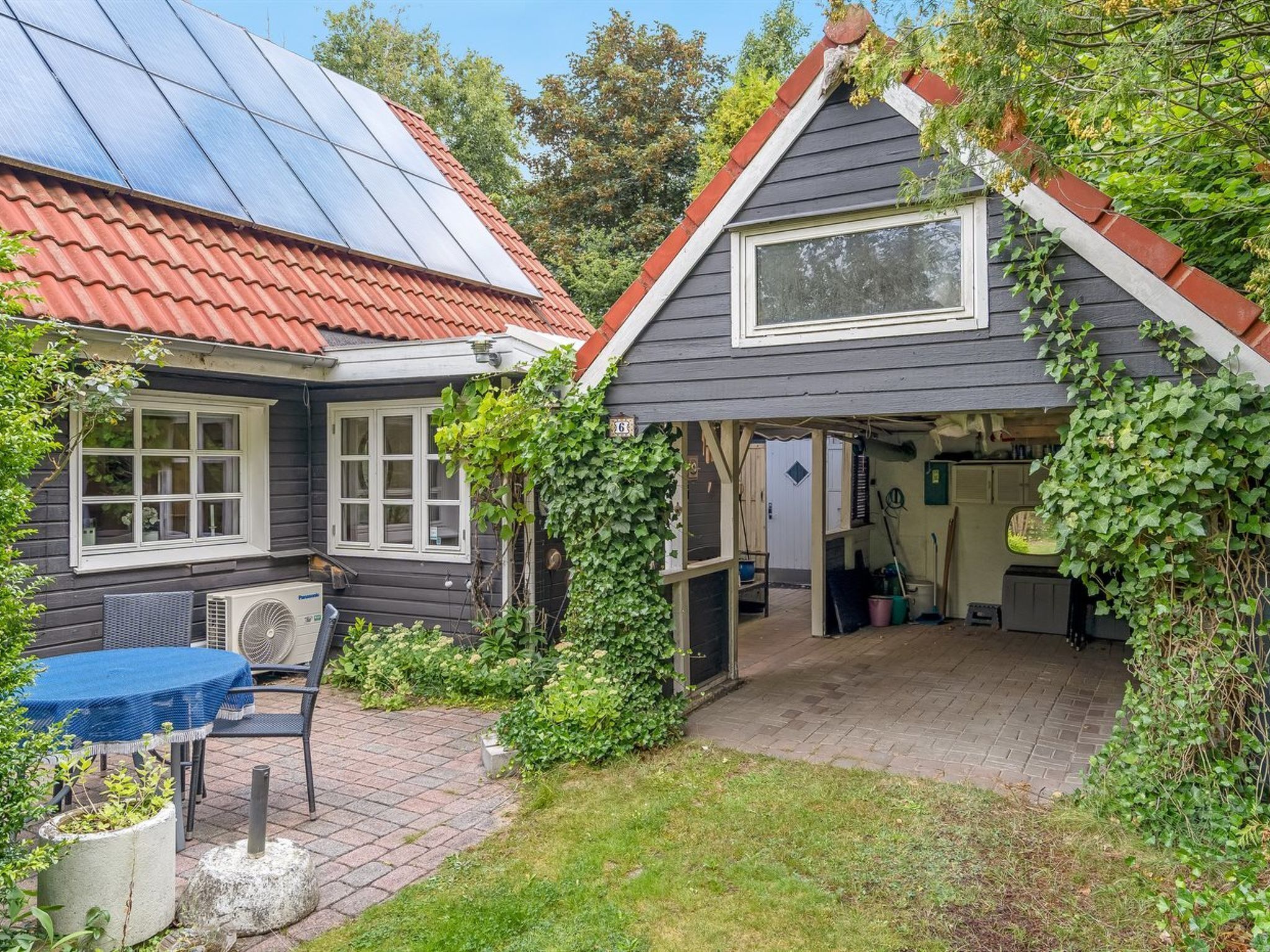 A house with a solar panel roof, a covered patio, and a garden area.