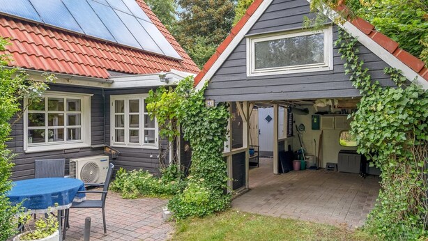 Una casa con techo de paneles solares, un porche cubierto y un jardín.