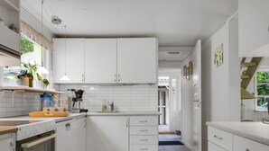 Una cocina moderna con armarios blancos, horno empotrado y encimera con diversos electrodomésticos.