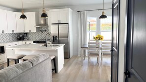 A modern kitchen with white cabinets, a stainless steel refrigerator, and a central island. - The Clark House St. Augustine (Saint Augustine)