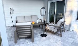 Eine Terrasse mit einer Couch, einem Tisch, zwei Stühlen und zwei Stehlampen.