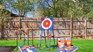 A backyard with a wooden fence, two bean bags, a swing set, and a target board. - Dog-Friendly Arvada Home with Fire Pit, 18 Min to Red Rocks & Near Denver (Arvada)